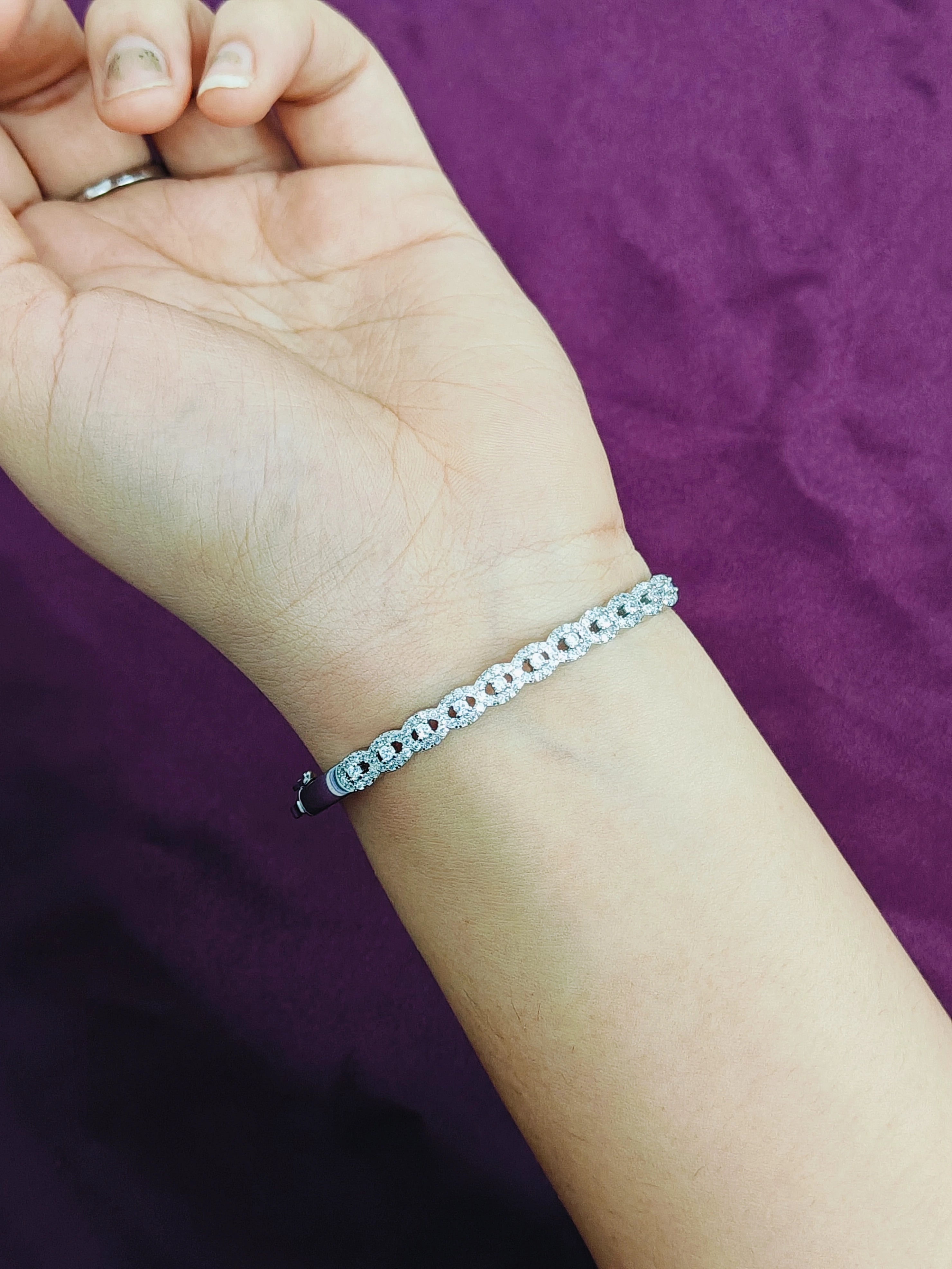Silver bracelet on a wrist against a purple background